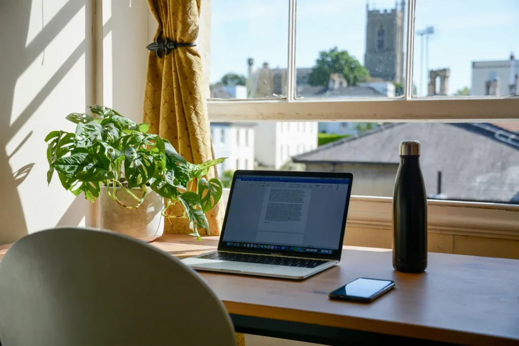 Laptop on a desk beside a sunny window