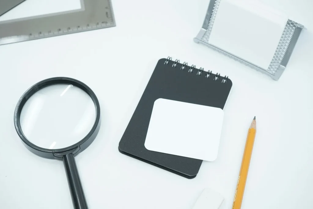 Magnifying glass beside a notebook and pencil