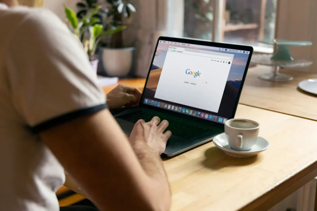 Person searching on Google on a laptop at a cafe table