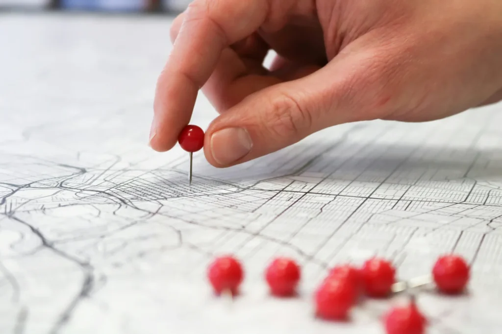 Hand placing a red pin on a map