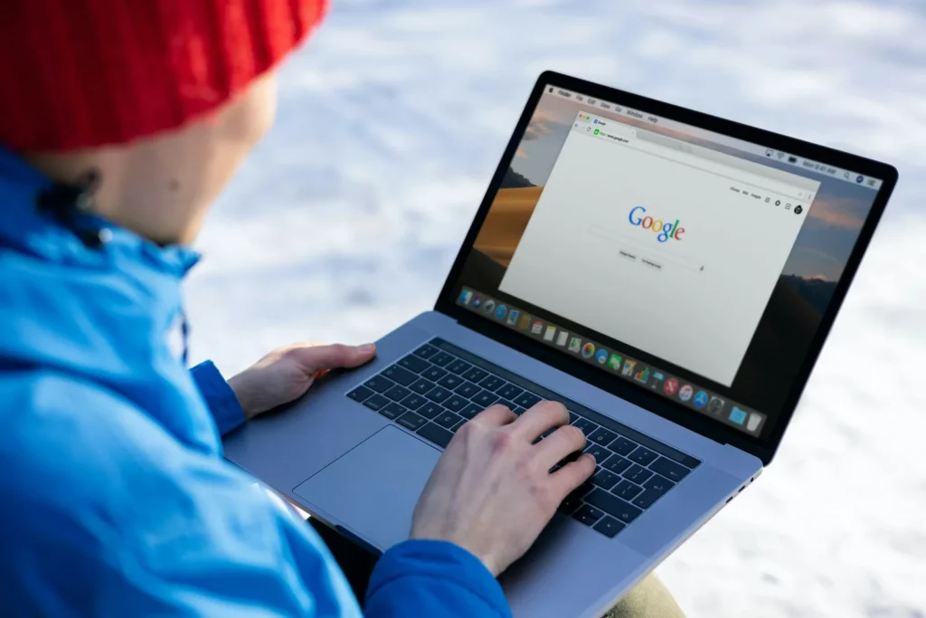 Person in a winter jacket using a search engine on a laptop