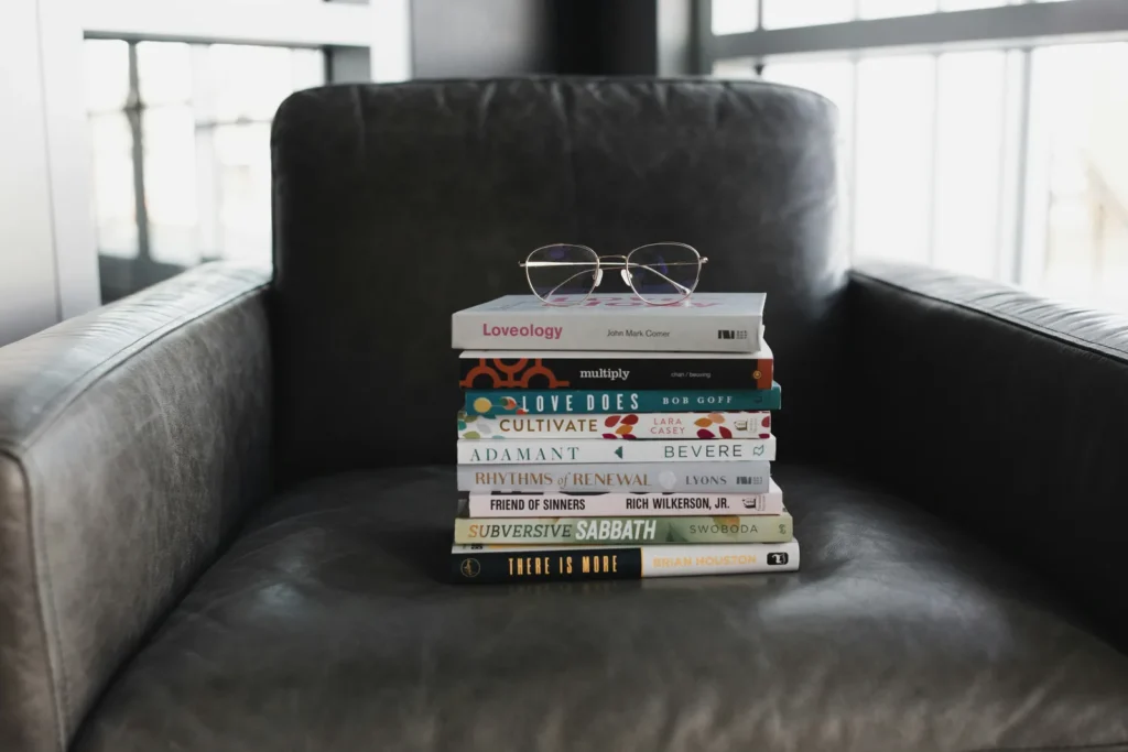 Stack of books with reading glasses on a leather chair