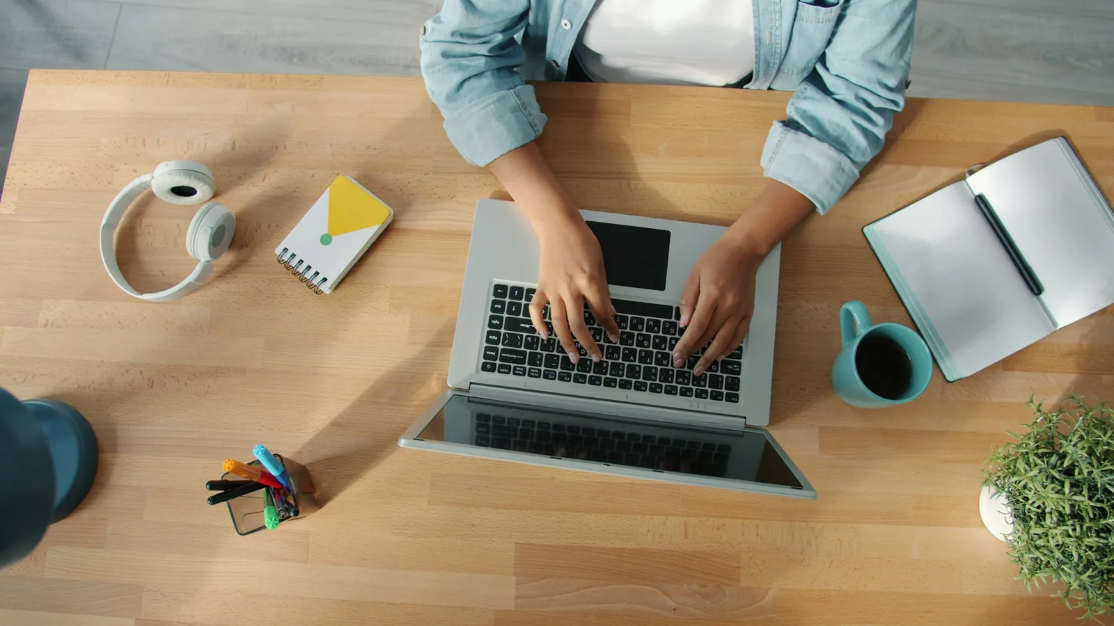 Person typing on a laptop at a wooden desk