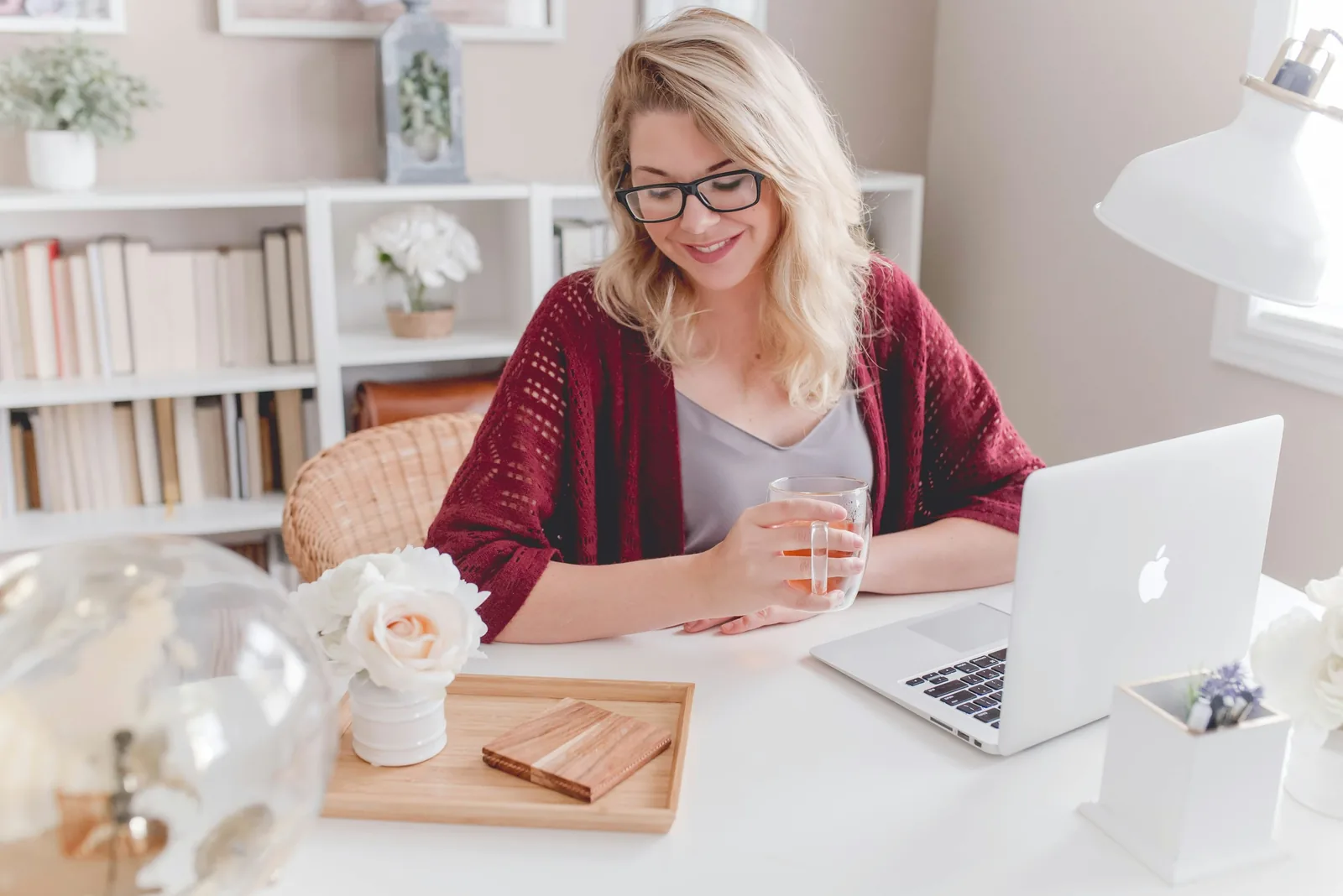 Woman smiling at her laptop with a mug of tea