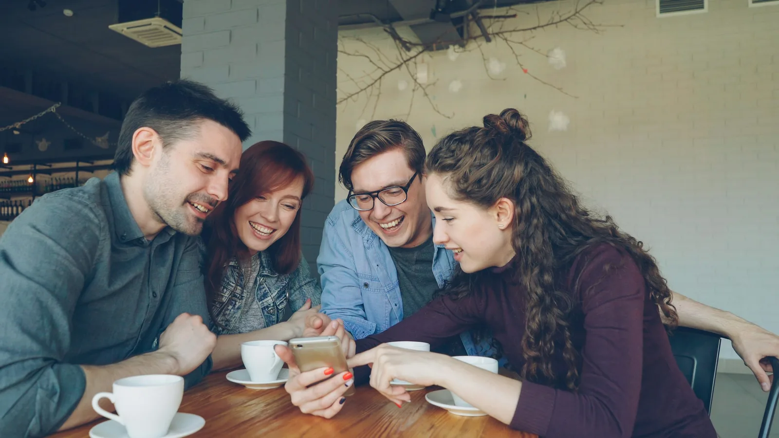 Friends laughing together at a post on a phone